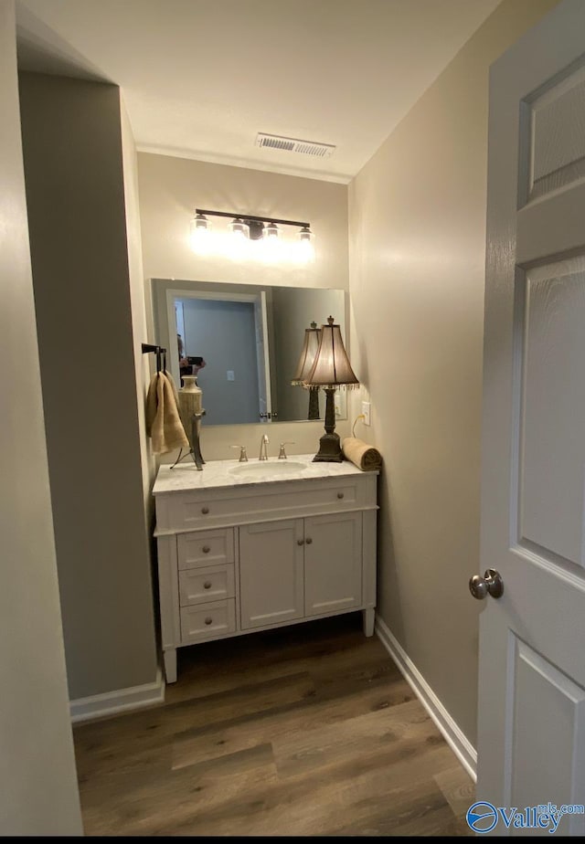 bathroom with visible vents, baseboards, vanity, and wood finished floors