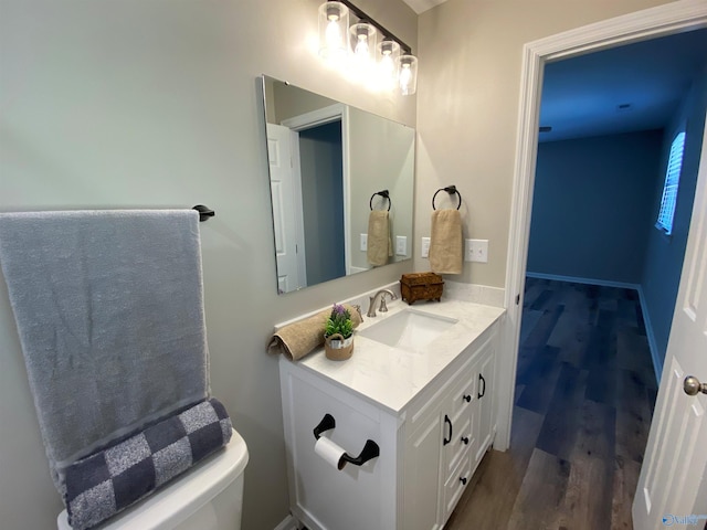 bathroom featuring toilet, vanity, and wood finished floors