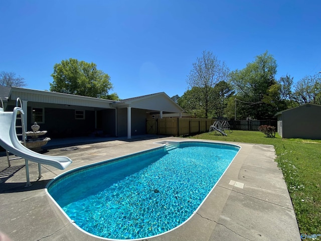 view of swimming pool featuring a fenced in pool, a patio, a water slide, a fenced backyard, and a yard