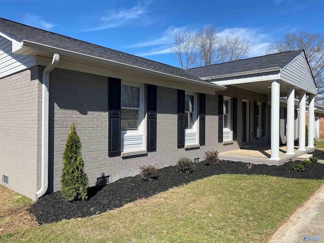 view of side of property with crawl space, a lawn, and brick siding