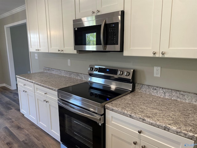 kitchen featuring dark wood-type flooring, appliances with stainless steel finishes, ornamental molding, and white cabinets