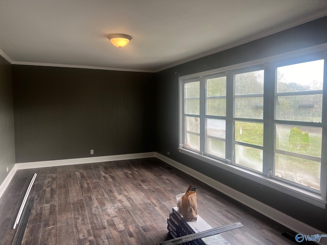 unfurnished room with ornamental molding and dark wood-type flooring