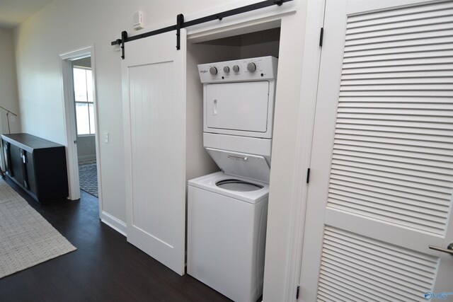 washroom with dark hardwood / wood-style floors, a barn door, and stacked washer / dryer