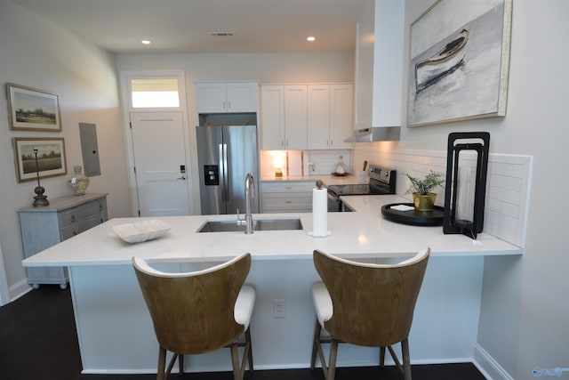 kitchen featuring kitchen peninsula, sink, white cabinets, a breakfast bar, and appliances with stainless steel finishes