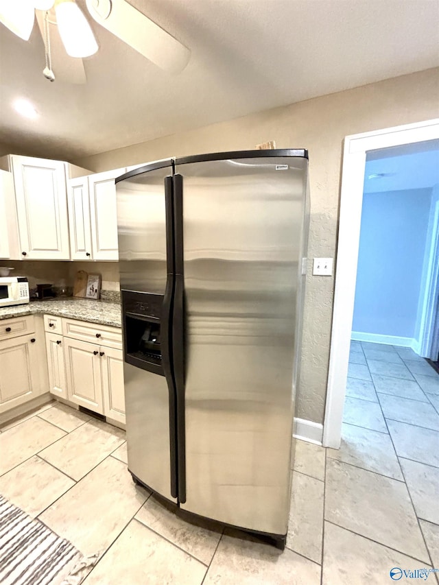 753 Walnut St, Gadsden, AL 35901 - kitchen with stainless steel refrigerator with ice dispenser, white microwave, a ceiling fan, light stone countertops, and white cabinetry