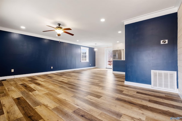 empty room featuring crown molding, visible vents, light wood-style floors, and a ceiling fan