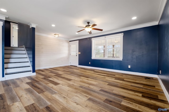 interior space featuring crown molding, stairway, baseboards, a ceiling fan, and wood finished floors