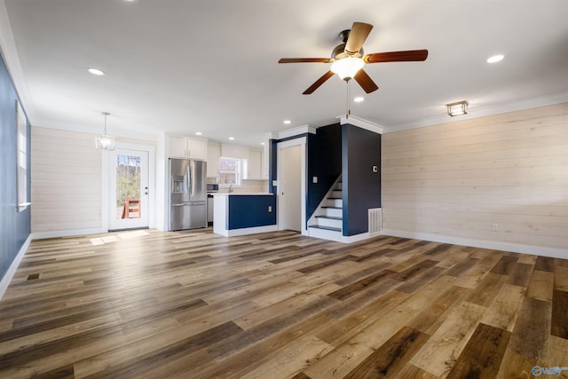 unfurnished living room with stairway, recessed lighting, ornamental molding, a ceiling fan, and wood finished floors