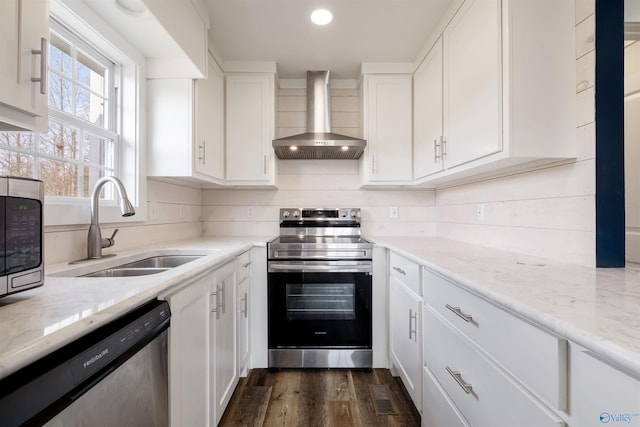 kitchen featuring white cabinetry, wall chimney exhaust hood, a sink, and stainless steel appliances
