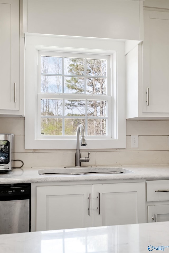 kitchen featuring a sink, white cabinets, light countertops, and dishwasher