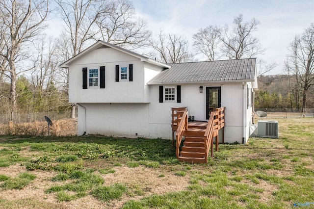tri-level home with a wooden deck, a front yard, central air condition unit, and metal roof