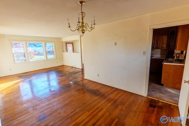 unfurnished dining area with dark hardwood / wood-style flooring, sink, and an inviting chandelier