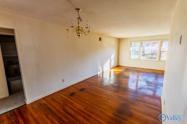 unfurnished room with an inviting chandelier and hardwood / wood-style flooring