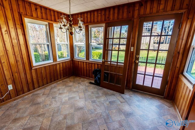 interior space featuring plenty of natural light, wood walls, and a chandelier