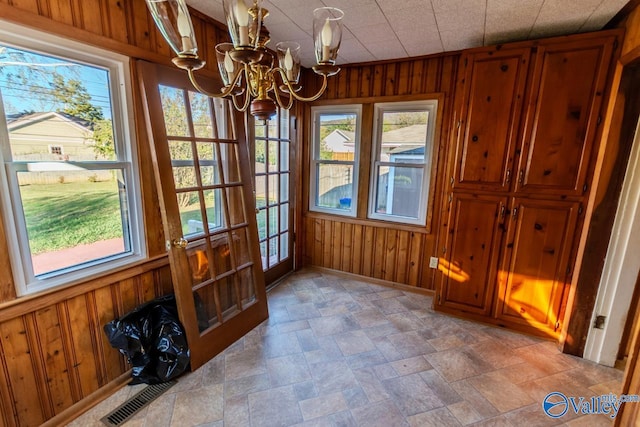 dining area with wood walls, french doors, and a chandelier