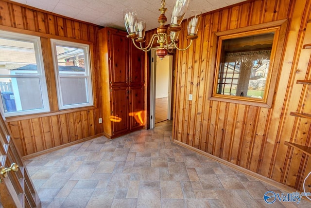 unfurnished dining area featuring wood walls and an inviting chandelier