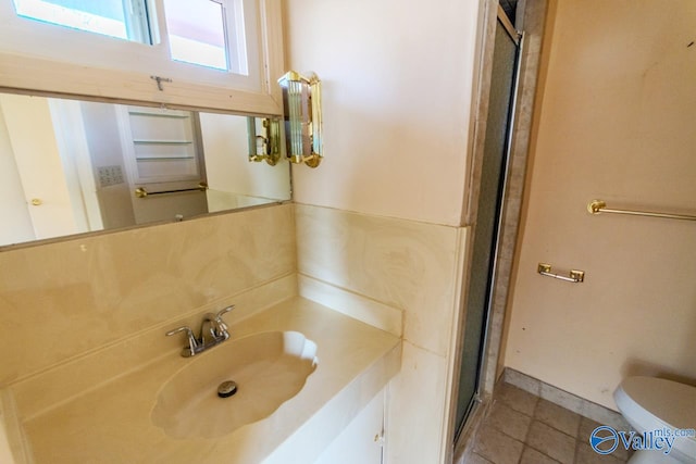 bathroom with toilet, a shower with door, and sink