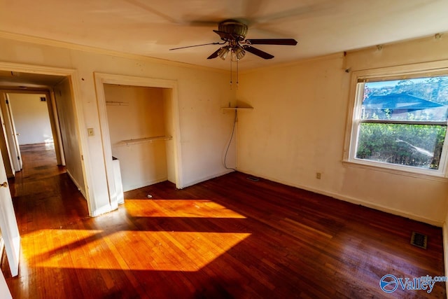 unfurnished bedroom with a closet, ceiling fan, crown molding, and dark wood-type flooring