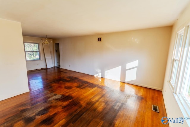 unfurnished room featuring a notable chandelier and dark hardwood / wood-style flooring