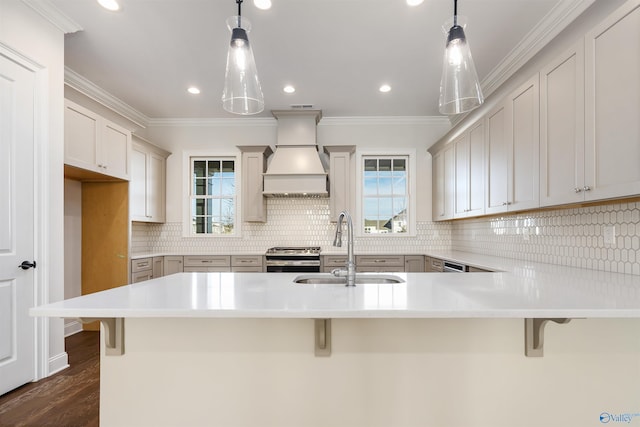 kitchen featuring sink, a breakfast bar, hanging light fixtures, and custom range hood