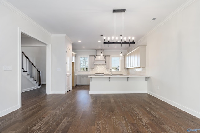 kitchen featuring decorative light fixtures, ornamental molding, kitchen peninsula, and a kitchen breakfast bar