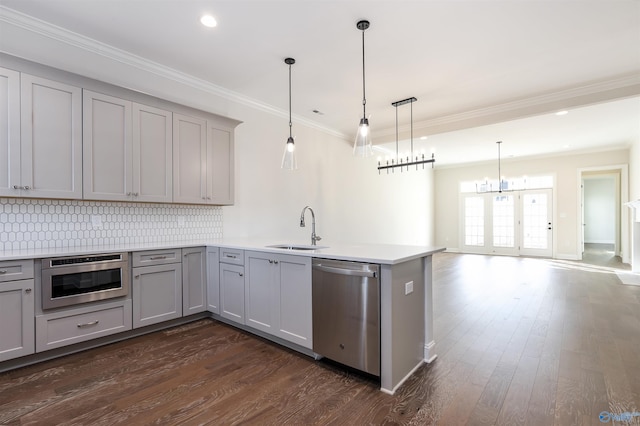 kitchen with decorative light fixtures, sink, decorative backsplash, kitchen peninsula, and stainless steel appliances