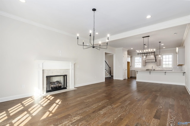 unfurnished living room with an inviting chandelier, ornamental molding, and dark hardwood / wood-style floors