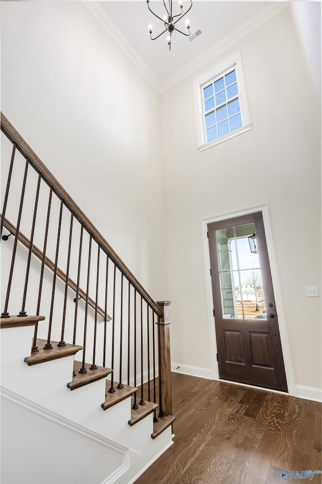 foyer entrance with an inviting chandelier, ornamental molding, dark hardwood / wood-style floors, and a high ceiling