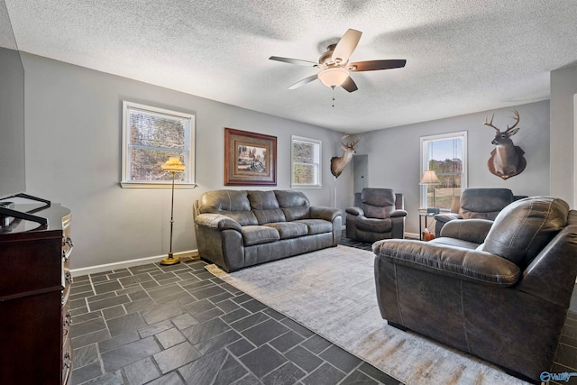 living room featuring a wealth of natural light, ceiling fan, and a textured ceiling