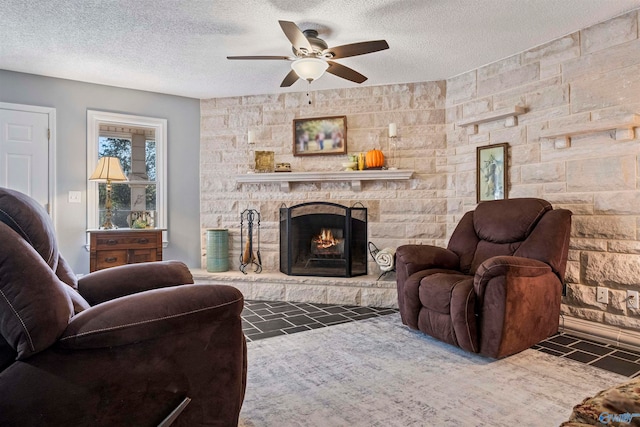 living room featuring a fireplace, ceiling fan, and a textured ceiling