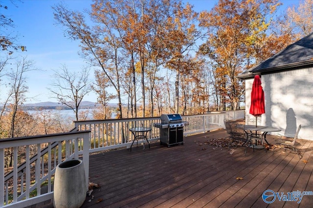 wooden terrace with area for grilling and a water and mountain view