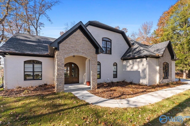 french country inspired facade featuring french doors and a front lawn