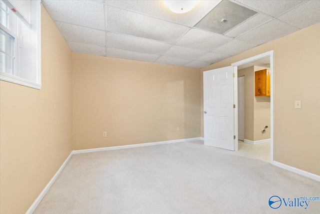 carpeted spare room featuring a drop ceiling