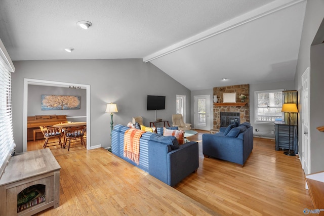 living room featuring a stone fireplace, wood-type flooring, lofted ceiling with beams, and a textured ceiling