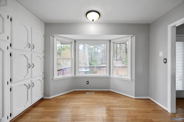 unfurnished dining area featuring light hardwood / wood-style flooring and a textured ceiling