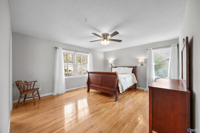 bedroom with a textured ceiling, ceiling fan, and light hardwood / wood-style floors