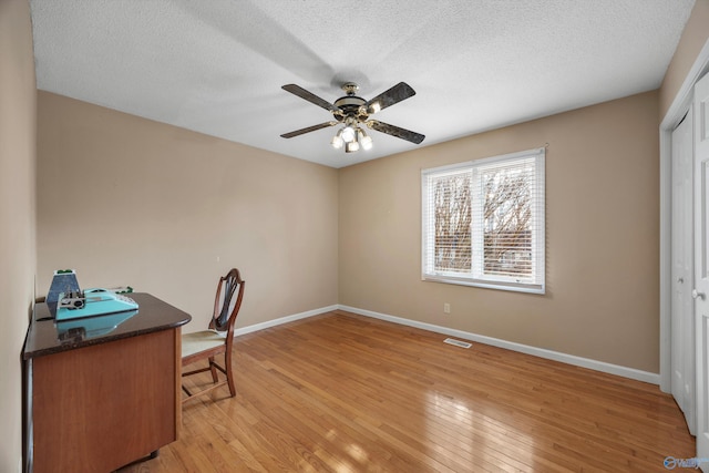 office area featuring ceiling fan, light hardwood / wood-style flooring, and a textured ceiling