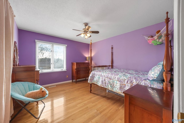 bedroom with a textured ceiling, ceiling fan, and light hardwood / wood-style flooring