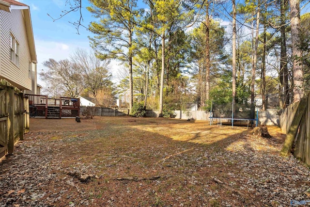 view of yard featuring a wooden deck and a trampoline