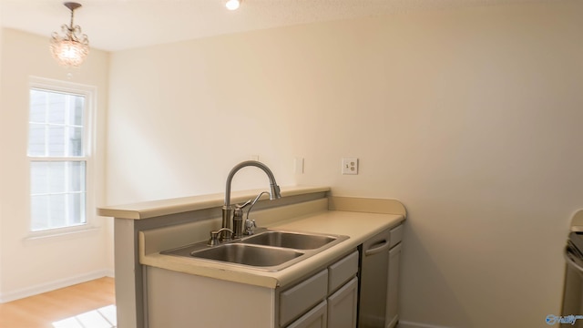 kitchen with decorative light fixtures, dishwasher, sink, gray cabinetry, and light wood-type flooring