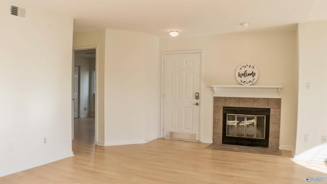 unfurnished living room with a tile fireplace and hardwood / wood-style floors