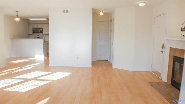 unfurnished living room featuring a fireplace and light hardwood / wood-style floors