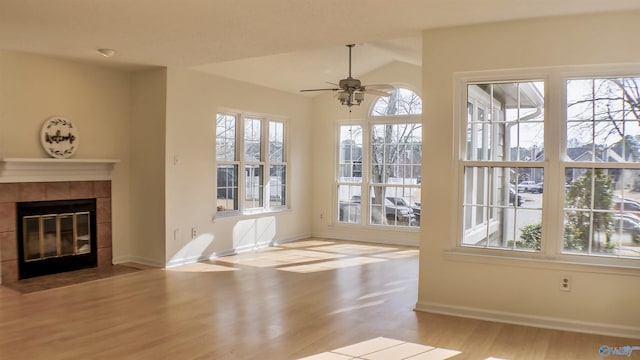 interior space featuring a tiled fireplace, lofted ceiling, a wealth of natural light, and ceiling fan