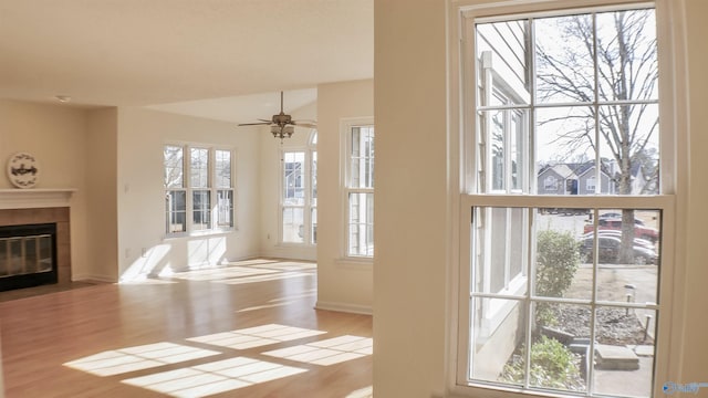 entryway featuring ceiling fan, light hardwood / wood-style floors, and a tile fireplace