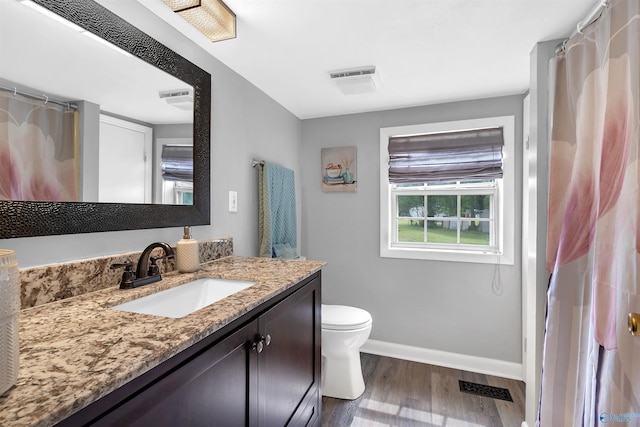 bathroom featuring wood finished floors, visible vents, toilet, vanity, and baseboards