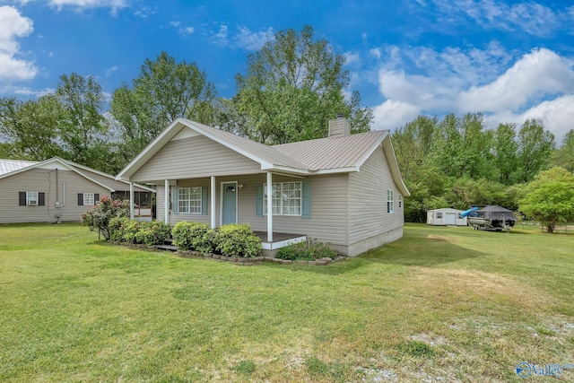 ranch-style home featuring metal roof, a chimney, a front yard, and covered porch