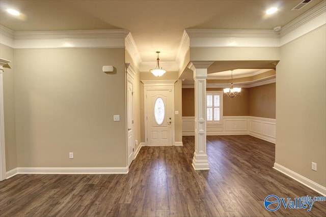 foyer entrance with dark hardwood / wood-style flooring, an inviting chandelier, ornate columns, and crown molding