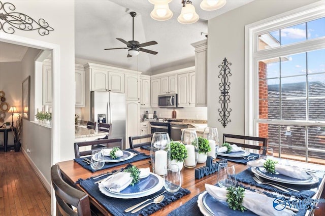 dining space featuring dark wood-style floors, baseboards, a ceiling fan, and vaulted ceiling