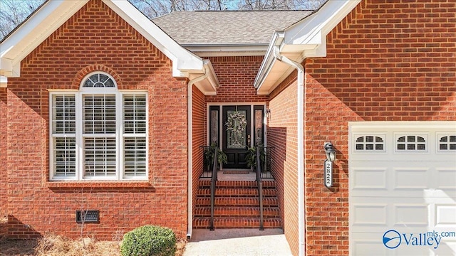 entrance to property featuring crawl space, a shingled roof, a garage, and brick siding