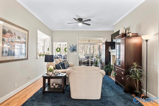 living room featuring baseboards, a ceiling fan, wood finished floors, and crown molding